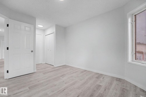Spacious room featuring light wood-finish flooring, white walls, a double-door closet, and a white framed window - 3704 39 Avenue, Edmonton, AB 