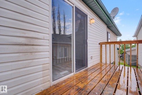 Exterior deck with wood-finish flooring, featuring a sliding glass door with a screen, and an exterior wall light fixture - 3704 39 Avenue, Edmonton, AB 
