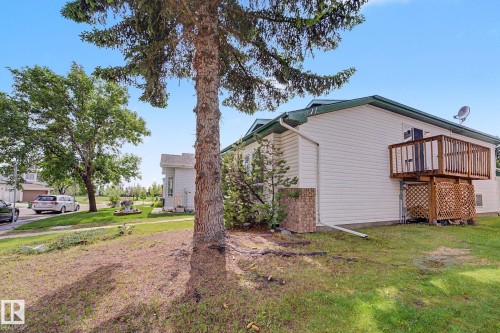Rear exterior featuring a two-level wood deck with lattice screening, white siding, and a dark green roof - 3704 39 Avenue, Edmonton, AB 