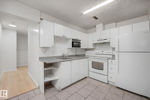 Contemporary kitchen featuring white cabinetry, a light-colored countertop, and a white tiled backsplash - 3704 39 Avenue, Edmonton, AB 