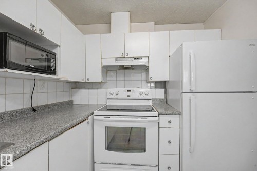Kitchen featuring white cabinetry, a tile backsplash, and speckled countertops - 3704 39 Avenue, Edmonton, AB 