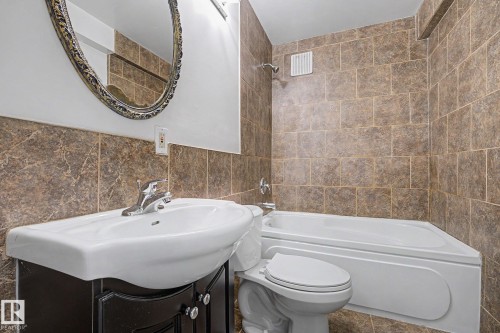 Bathroom featuring a white drop-in sink, dark wood-finish vanity, and a white bathtub - 3704 39 Avenue, Edmonton, AB 