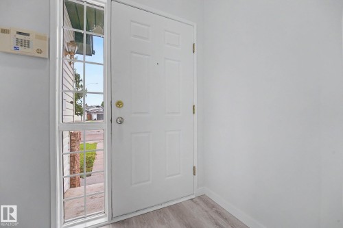 Entryway featuring a white paneled door, a grid-patterned sidelight, and light-toned wood-finish flooring - 3704 39 Avenue, Edmonton, AB 