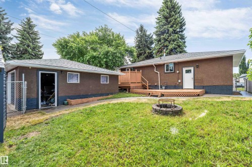 Expansive backyard featuring a detached garage with a single vehicle bay, a wood deck, and a built-in fire pit - 6404 88 Avenue, Edmonton, AB 
