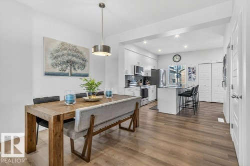 Open-concept dining and kitchen area featuring wood-finish flooring, recessed lighting, and a modern kitchen island with seating - 3708 42 Avenue, Beaumont, AB 