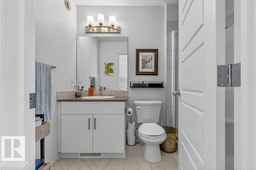 Bathroom featuring a single vanity with a stone-finish countertop, undermount sink, and white cabinetry - 3708 42 Avenue, Beaumont, AB 