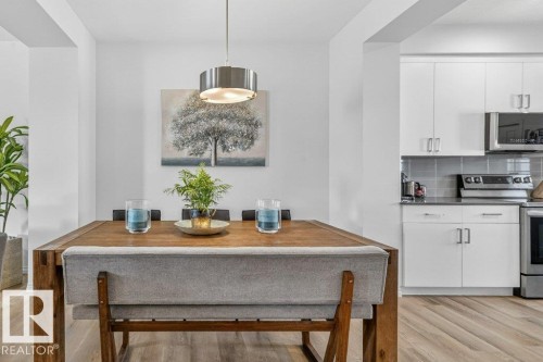 Dining area featuring a wood-finish table, a contemporary pendant light fixture, and wood-finish flooring - 3708 42 Avenue, Beaumont, AB 