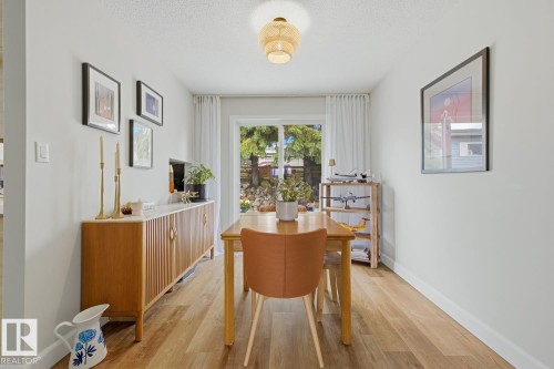 Bright dining area featuring wood-finish flooring, white walls, and a contemporary ceiling fixture - 3504 102 Avenue, Edmonton, AB 