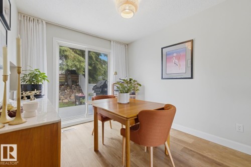 Dining area featuring wood-finish flooring and a contemporary overhead light fixture - 3504 102 Avenue, Edmonton, AB 