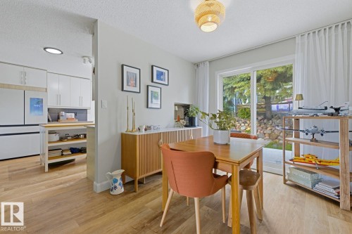 Bright dining area featuring wood-finish flooring and a contemporary light fixture - 3504 102 Avenue, Edmonton, AB 