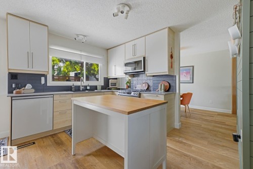 Contemporary kitchen featuring two-tone cabinetry with light-toned wood-finish lower cabinets and white upper cabinets - 3504 102 Avenue, Edmonton, AB 