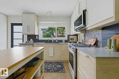 Contemporary kitchen featuring a stainless steel gas range, microwave, and dishwasher - 3504 102 Avenue, Edmonton, AB 