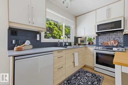 Modern kitchen featuring light-toned wood-finish lower cabinetry and contrasting white upper cabinets - 3504 102 Avenue, Edmonton, AB 