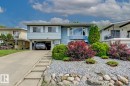 Split-level residence featuring light blue siding, white trim, and a concrete driveway - 3504 102 Avenue, Edmonton, AB 