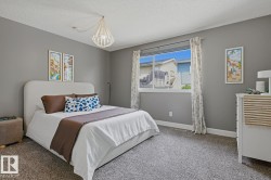 Inviting bedroom featuring gray wall paint, textured carpet flooring, and a large window with white trim - 