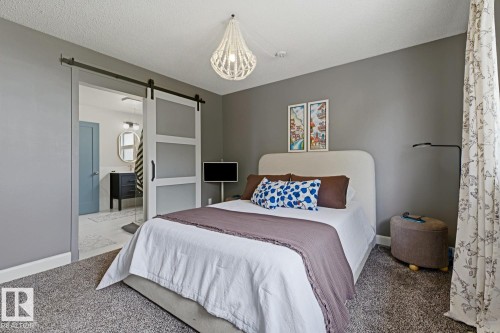 Barn door entry to an attached bathroom featuring a dark wood vanity with an oval mirror and a light blue interior door - 3504 102 Avenue, Edmonton, AB 