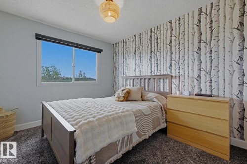 Room featuring a window with roller shade, textured wallpaper, carpeted flooring, and a ceiling-mounted light fixture - 3504 102 Avenue, Edmonton, AB 