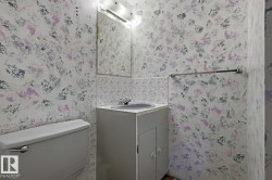 Compact bathroom featuring a white toilet, single vanity with a gray cabinet, and a wall-mounted mirror - 