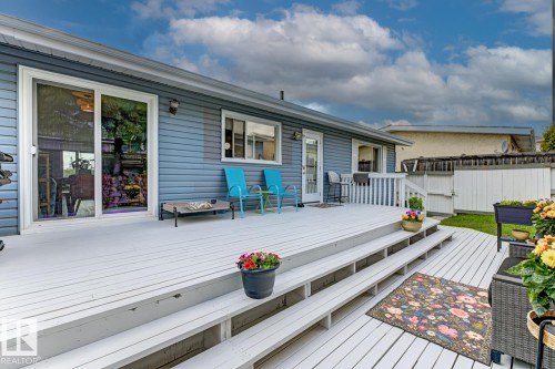 Expansive outdoor deck with multiple levels, white railings, and direct access to the interior via a sliding glass door and an additional entry door - 3504 102 Avenue, Edmonton, AB 