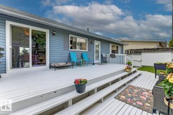 Expansive outdoor deck with multiple levels, white railings, and direct access to the interior via a sliding glass door and an additional entry door - 