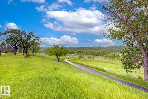 Expansive green landscape featuring a paved pathway, mature trees, and a distant tree line under a blue sky with clouds - 3504 102 Avenue, Edmonton, AB 