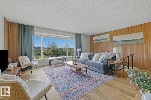 Spacious room featuring a prominent bay window with exterior scenery, wood-finish flooring, and slatted wood-paneled walls - 3504 102 Avenue, Edmonton, AB 