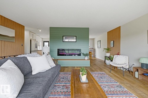 Living area featuring wood-finish flooring and a central fireplace with a horizontal hearth - 3504 102 Avenue, Edmonton, AB 