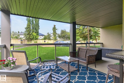 Covered patio featuring a solid ceiling, concrete flooring, and a glass panel railing system - 122 279 Suder Greens Drive, Edmonton, AB 