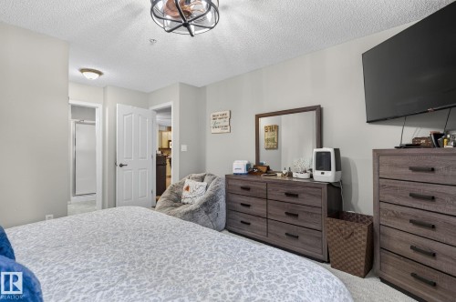 Bedroom featuring light gray wall paint, textured ceiling, and carpeted flooring - 122 279 Suder Greens Drive, Edmonton, AB 