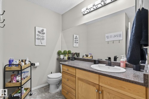 Bathroom featuring a vanity with a dark speckled countertop, an undermount sink, and a matte black faucet - 122 279 Suder Greens Drive, Edmonton, AB 