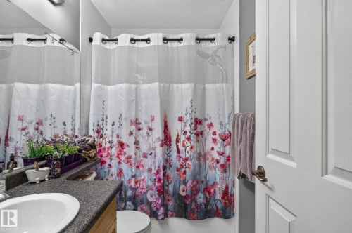 Bathroom featuring a built-in vanity with a speckled countertop and an undermount sink - 122 279 Suder Greens Drive, Edmonton, AB 