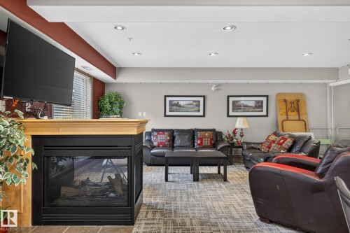 Living area featuring a natural wood mantel fireplace with a black firebox - 122 279 Suder Greens Drive, Edmonton, AB 