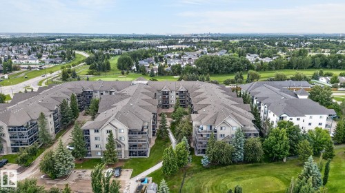 Expansive condominium complex featuring multiple buildings with private balconies, surrounded by mature evergreen and deciduous trees - 122 279 Suder Greens Drive, Edmonton, AB 