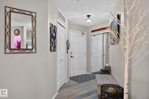 Entryway featuring wood-finish flooring, white panel doors, and a built-in overhead light fixture - 122 279 Suder Greens Drive, Edmonton, AB 