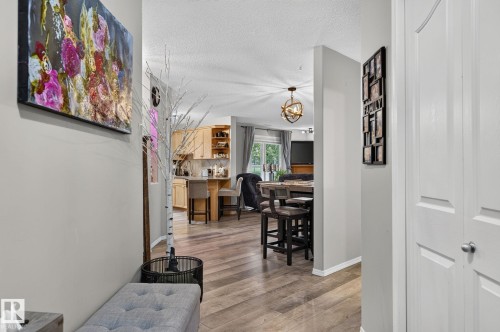 Hallway with light gray walls, wood-finish flooring, and white bi-fold closet doors - 122 279 Suder Greens Drive, Edmonton, AB 