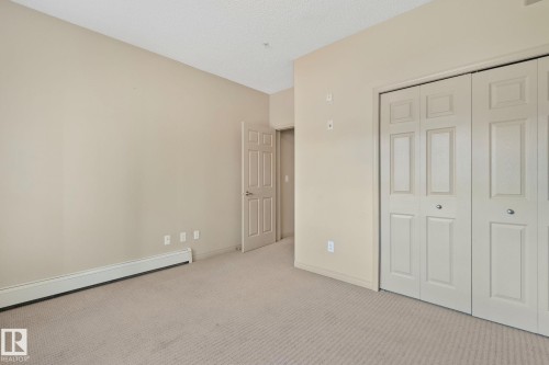 Neutral-toned interior room with soft carpet flooring, light beige wall paint, and a textured ceiling - 209 5280 Terwillegar Boulevard, Edmonton, AB - Indoor Photo Showing Other Room