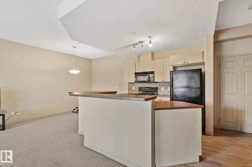 Kitchen area featuring light-toned cabinetry, a black refrigerator, and a built-in microwave - 209 5280 Terwillegar Boulevard, Edmonton, AB - Indoor Photo Showing Kitchen