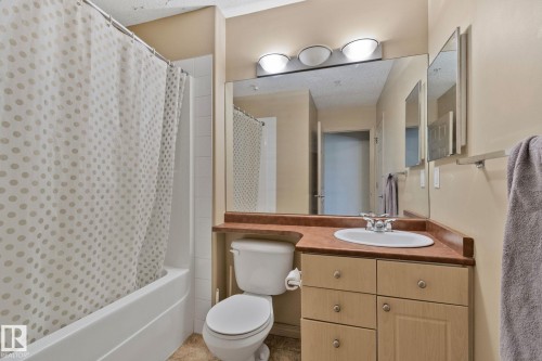 Full bathroom featuring a single vanity with an integrated sink, a large mirror, and a built-in bathtub with shower - 209 5280 Terwillegar Boulevard, Edmonton, AB - Indoor Photo Showing Bathroom