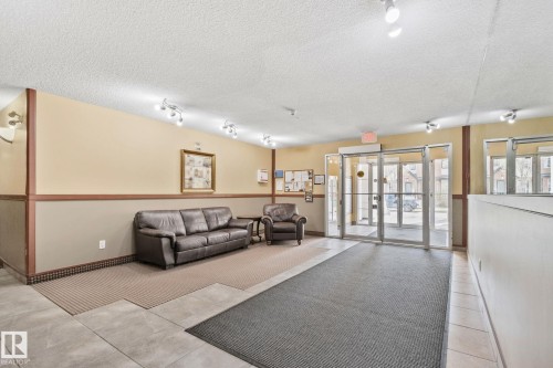 Building entrance featuring glass doors, track lighting, and a combination of carpet and tile flooring - 209 5280 Terwillegar Boulevard, Edmonton, AB - Indoor
