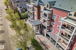 Multi-story building featuring red and tan siding, multiple private balconies, and a covered entrance - 