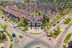 Aerial perspective of a residential neighborhood featuring rows of multi-story townhomes with varying exterior finishes and pitched roofs - 