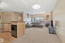 Open-concept living area with a built-in fireplace, sliding glass doors, and a breakfast bar with an integrated dishwasher - 209 5280 Terwillegar Boulevard, Edmonton, AB  - Indoor With Fireplace 