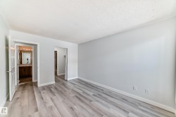 Spacious room featuring light wood-finish flooring, light gray wall paint, and white baseboards - 