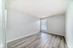Spacious room featuring wood-finish flooring, light grey wall paint, white baseboards, and a window with white trim - 