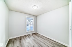 Room featuring wood-finish flooring, white baseboards, a white window frame, and a flush-mount ceiling light fixture - 
