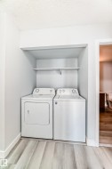 Dedicated laundry alcove featuring a white washer and dryer pair, an integrated storage shelf, and light wood-finish flooring - 