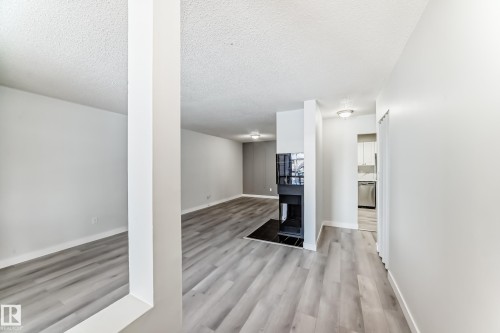Interior living space with wood-finish flooring, a built-in fireplace, and white painted walls - 23 1503 Mill Woods Road E, Edmonton, AB 