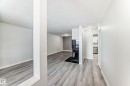 Interior living space with wood-finish flooring, a built-in fireplace, and white painted walls - 23 1503 Mill Woods Road E, Edmonton, AB 