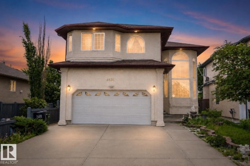 Stucco exterior with a two-car garage, featuring decorative window inserts and wall-mounted coach lights - 4831 154 Avenue, Edmonton, AB 