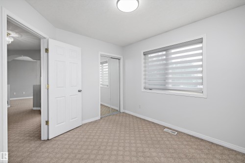 Bright room featuring patterned carpeting, a large window with horizontal blinds, and a mirrored closet - 4831 154 Avenue, Edmonton, AB 